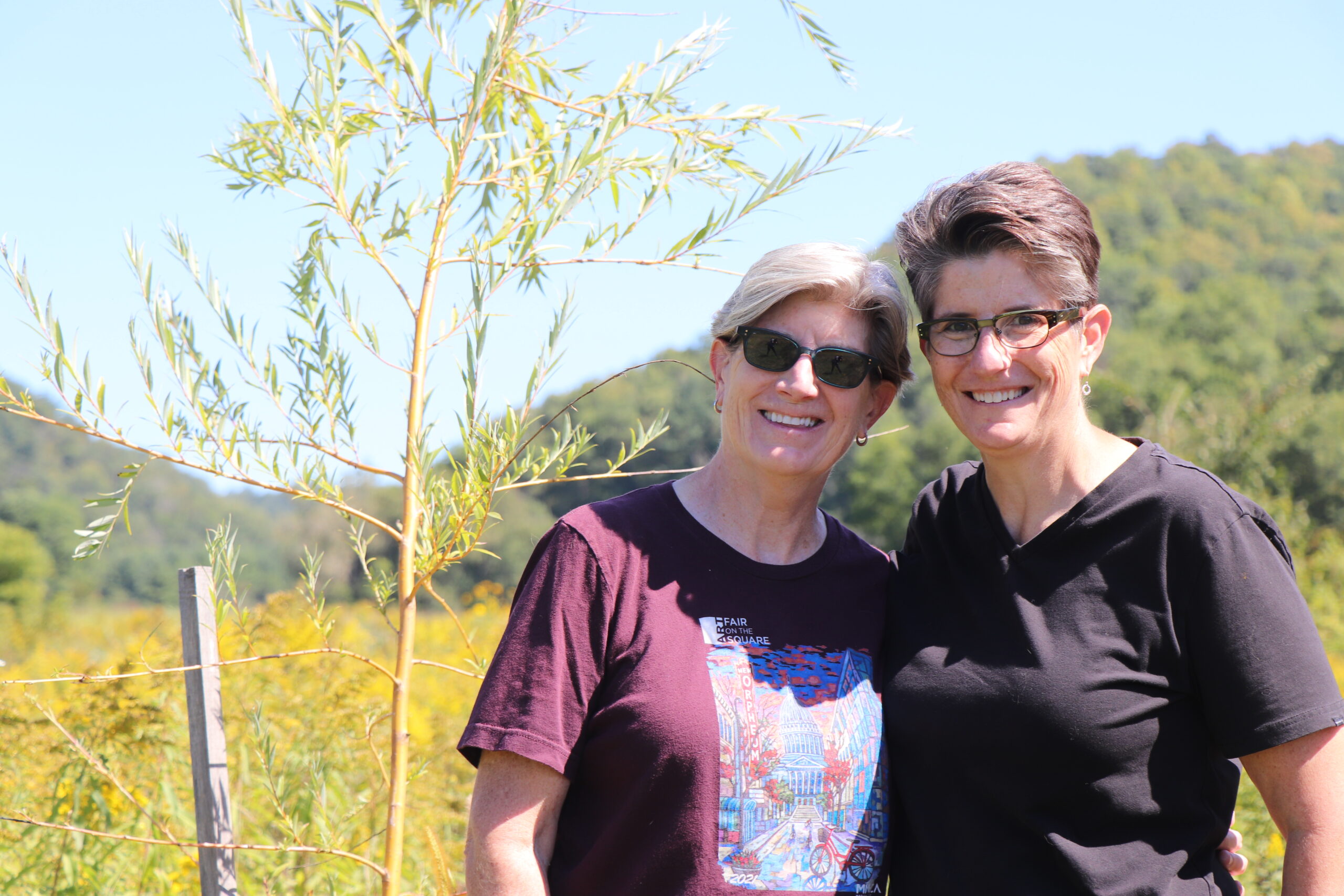 Carol Nikolaus and Sara Freedman pause next to a willow sapling they planted near the banks of Rulland’s Coulee Creek. Photo: Sydney Widell.